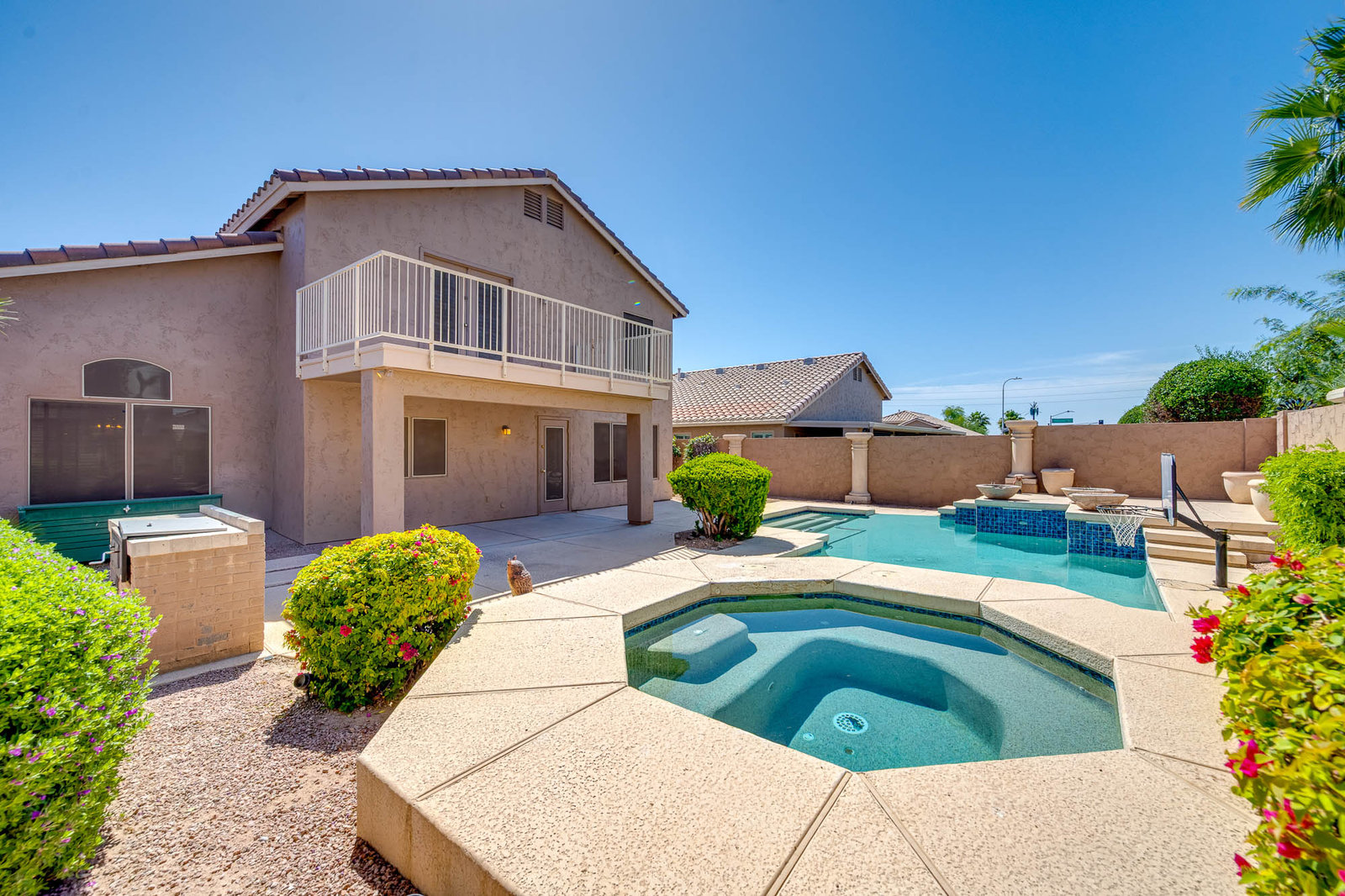 Backyard of a house with swimming pool, hot tub, and balcony
