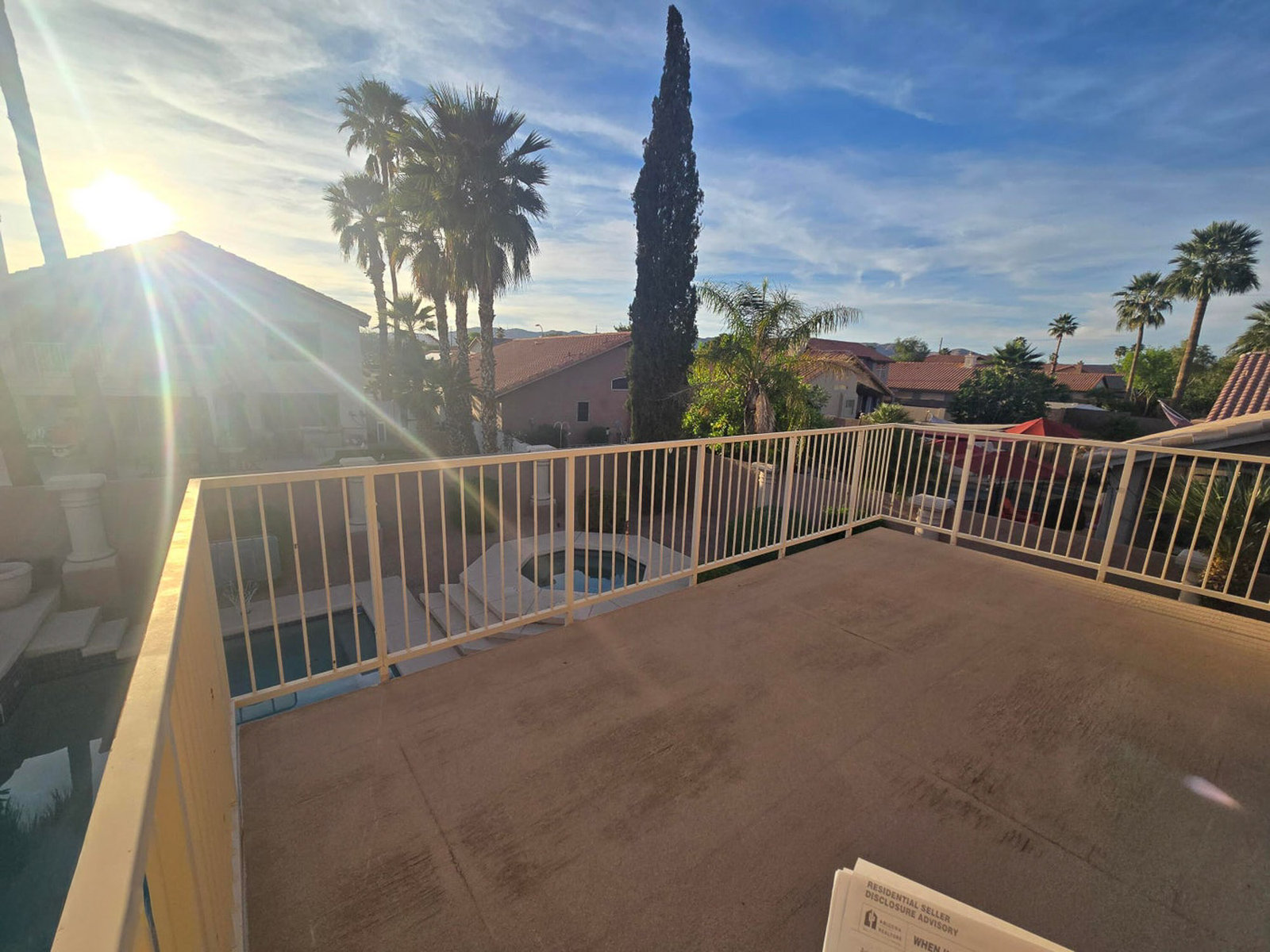 Balcony overlooking homes, palm trees, and a pool