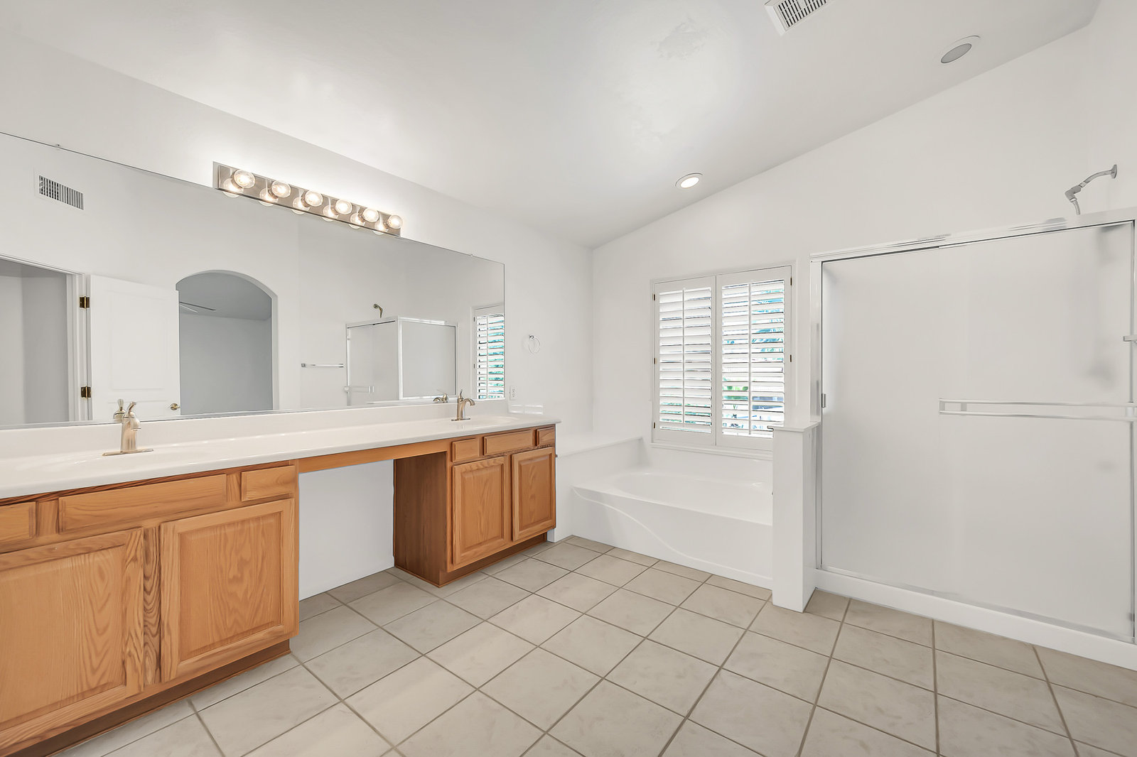 Bright bathroom with double vanity, tub, and shower