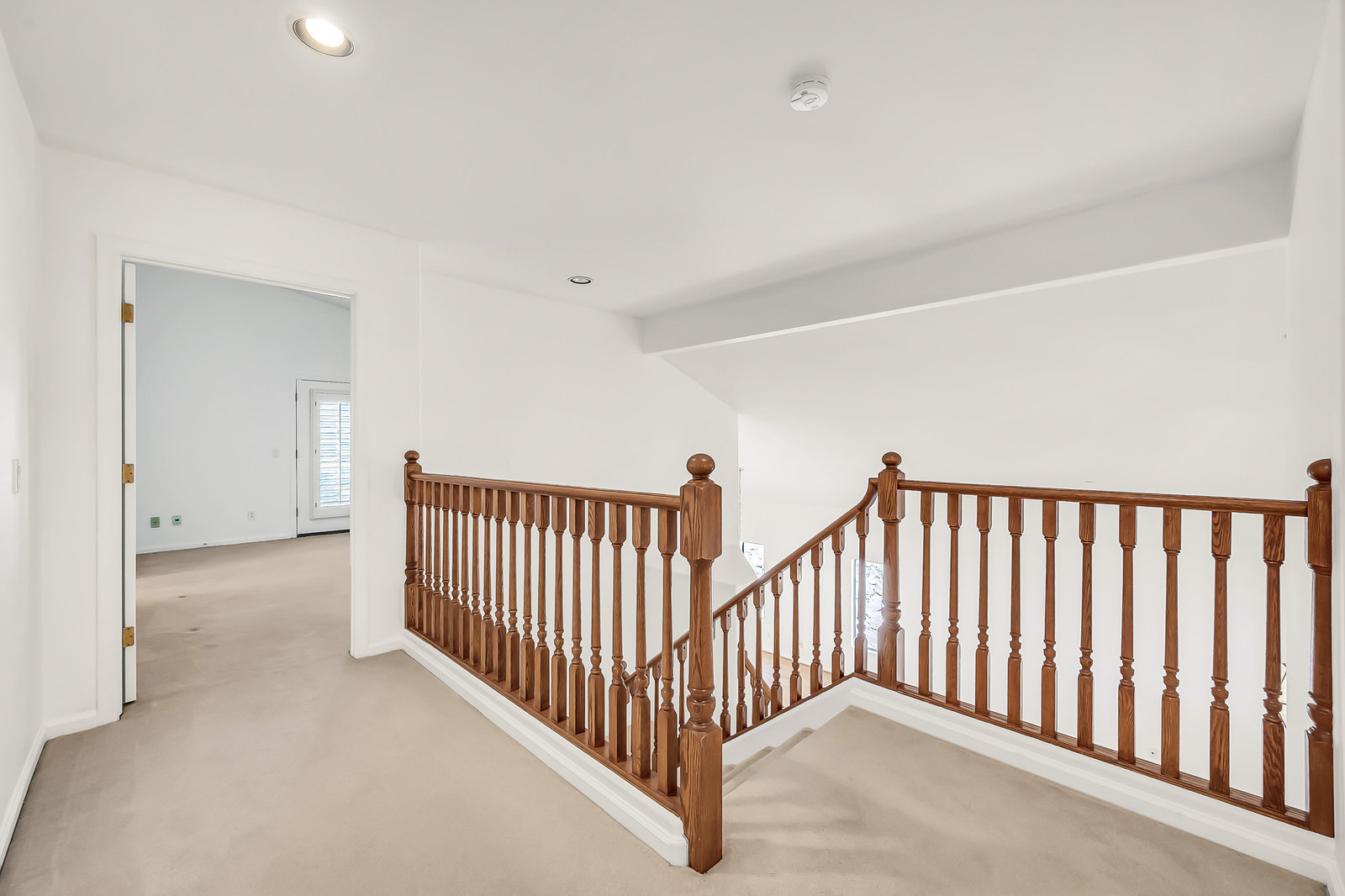 Carpeted hallway and wooden staircase banister