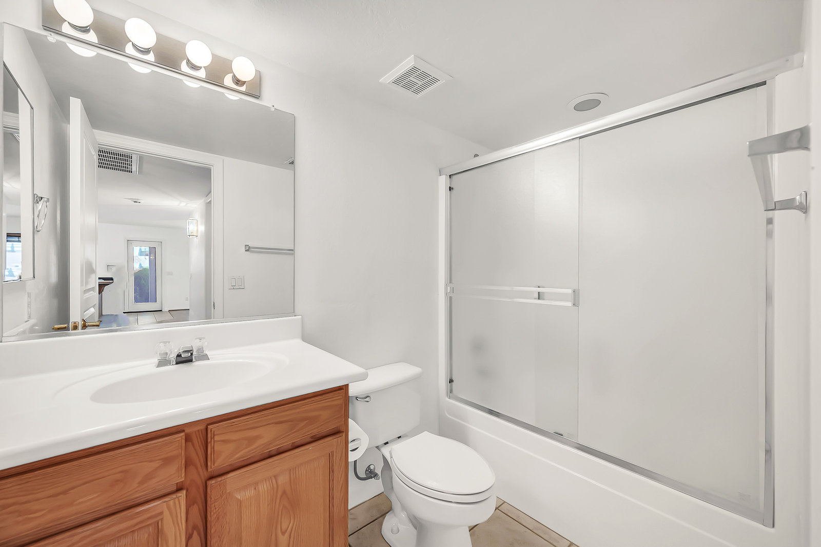 Clean bathroom with wood vanity, sink, toilet, and shower