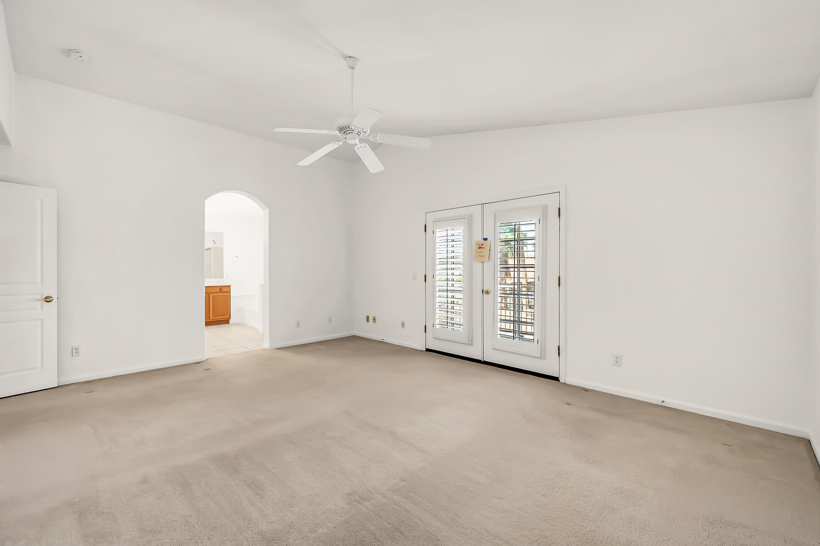 Empty living room with French doors and ceiling fan