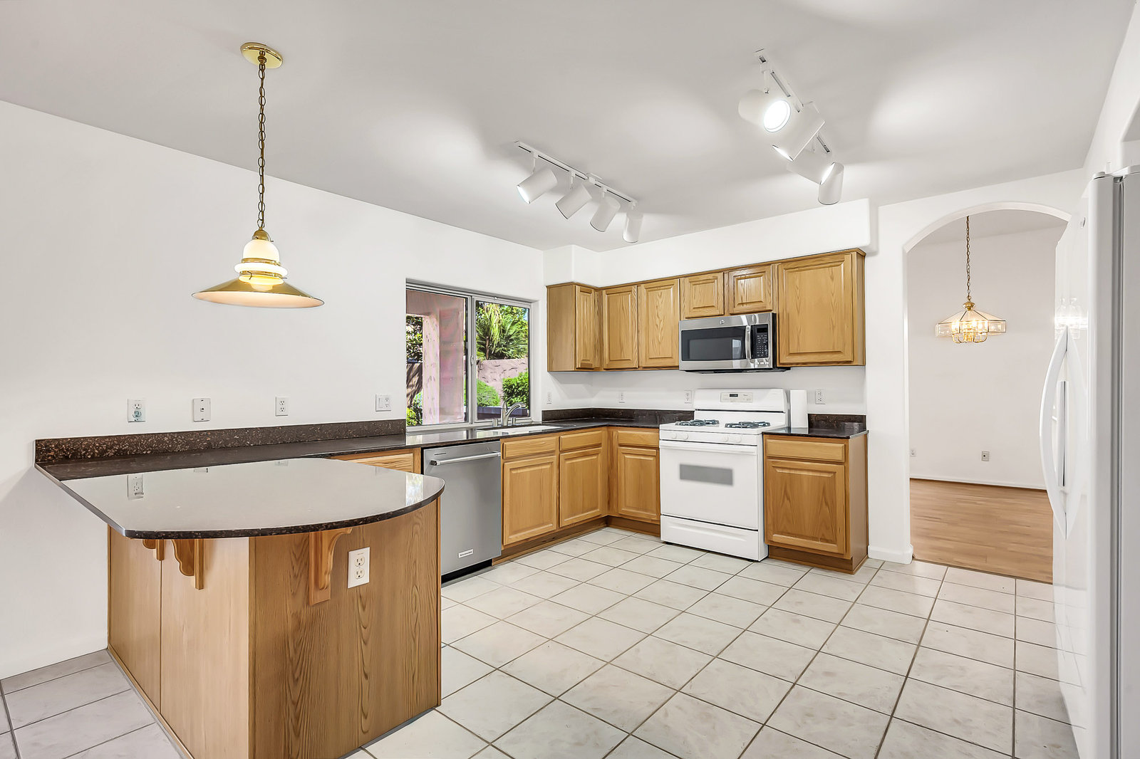 Kitchen with wood cabinets, white appliances, tile floor