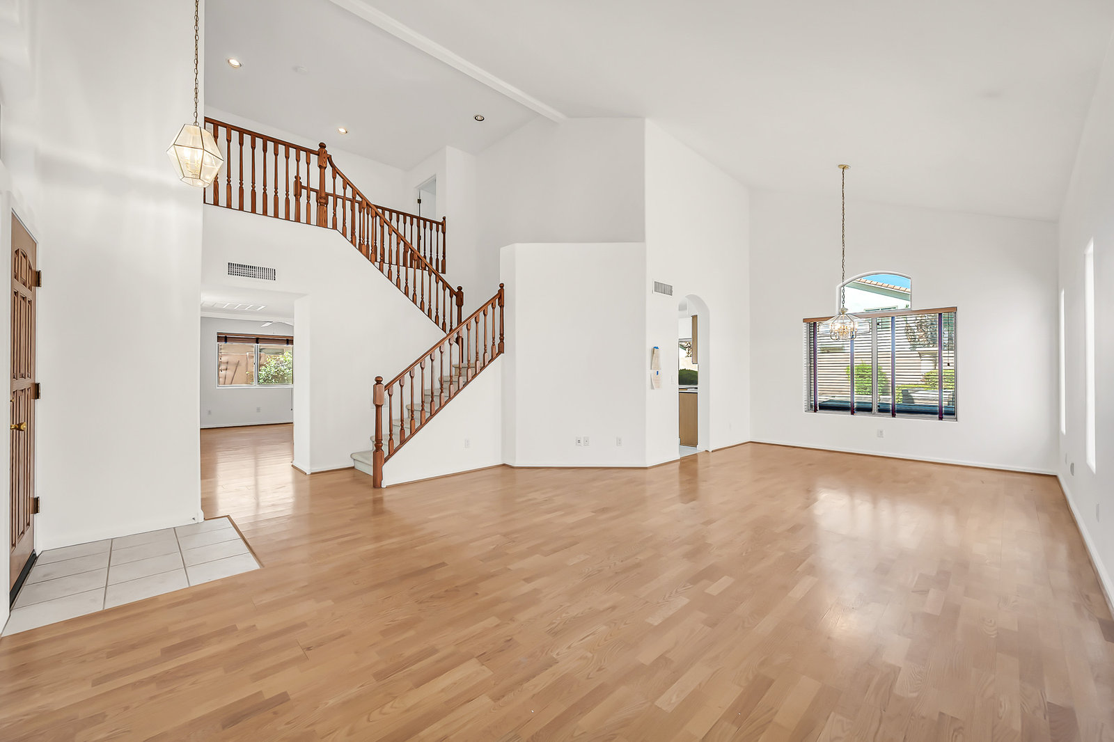 Open living space with wood floors and a grand staircase