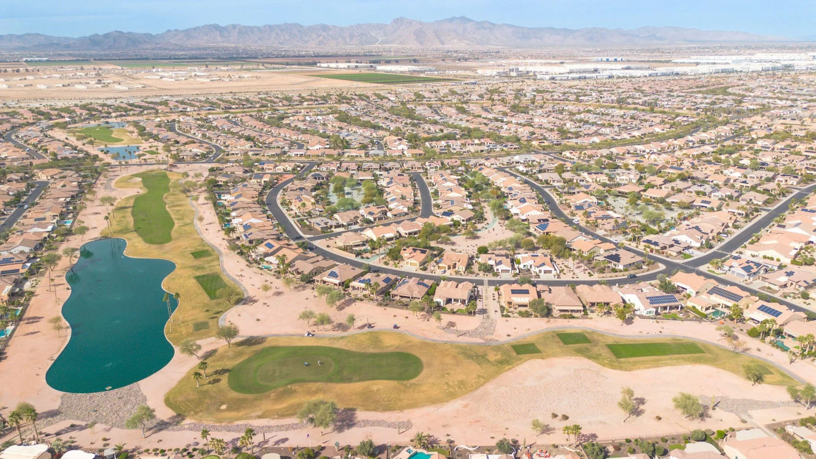 Aerial of a Goodyear golf community with lake and mountains