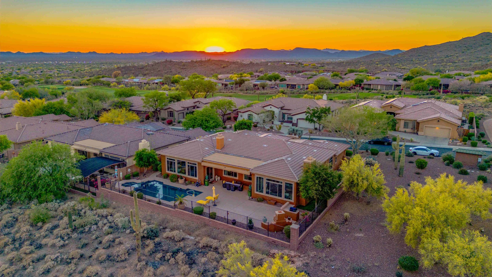 Aerial view of a house with a pool in a desert landscape at sunset