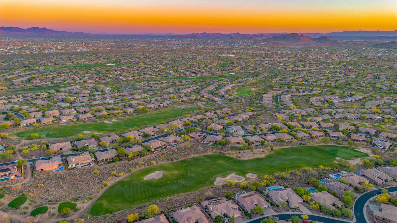 Aerial view of a residential area with golf courses at sunset
