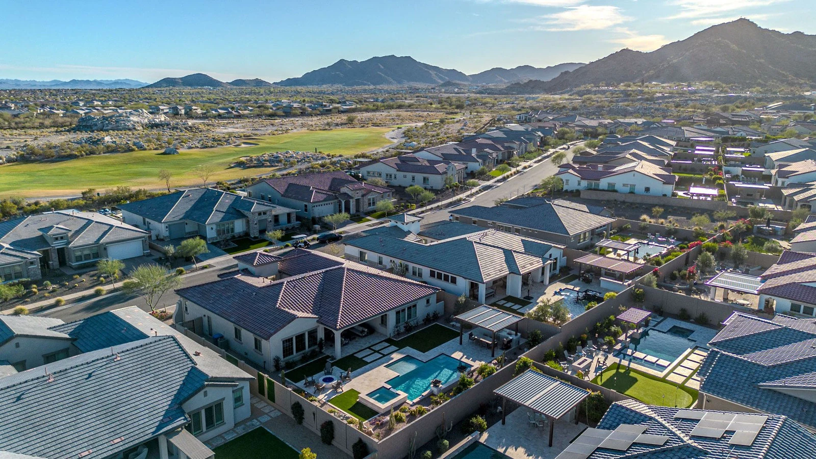 Aerial view of Verrado homes, pools and tree-lined streets below the White Tank Mountains in Buckeye, AZ
