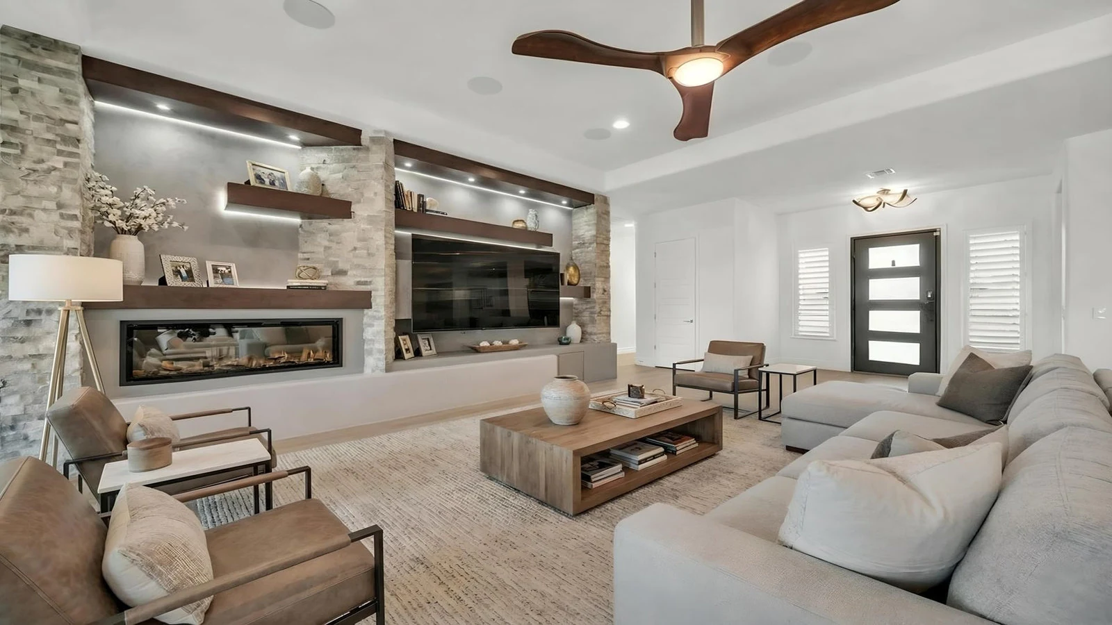 Spacious modern living room with large sectional, fireplace, and TV.