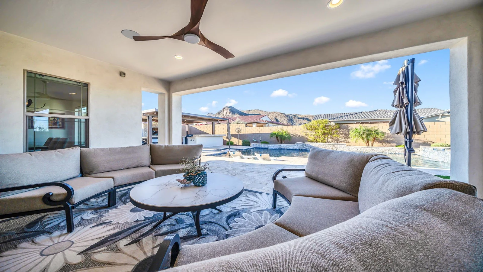 Covered patio with outdoor furniture, pool, and mountain view