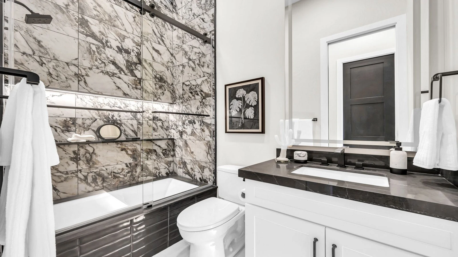 Modern bathroom with marble shower, toilet, and dark vanity