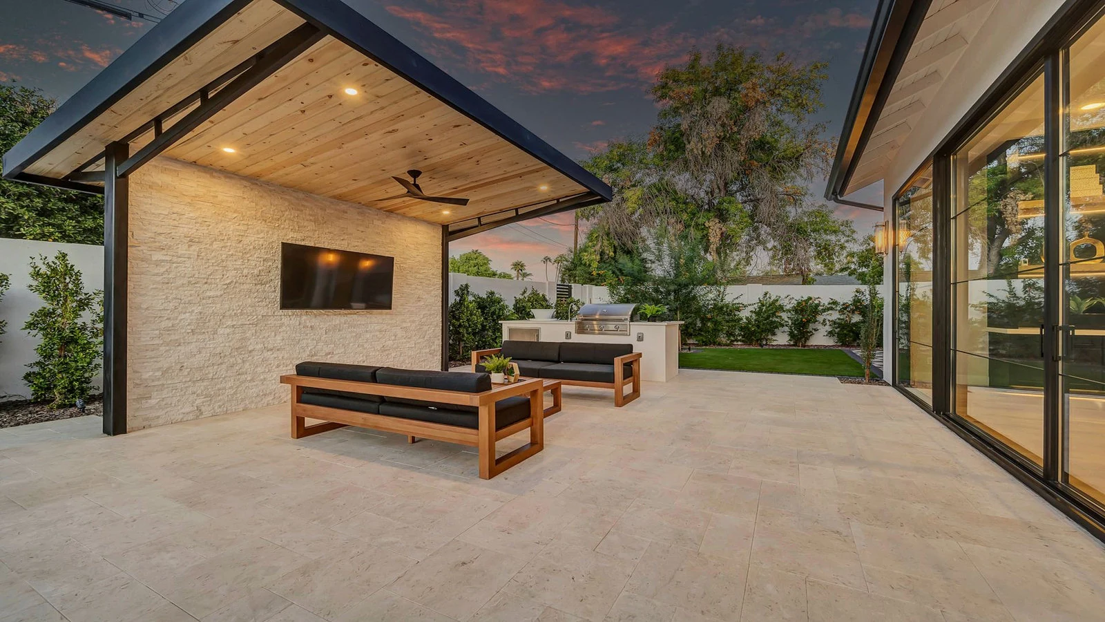 Modern patio with covered seating, TV, and outdoor kitchen