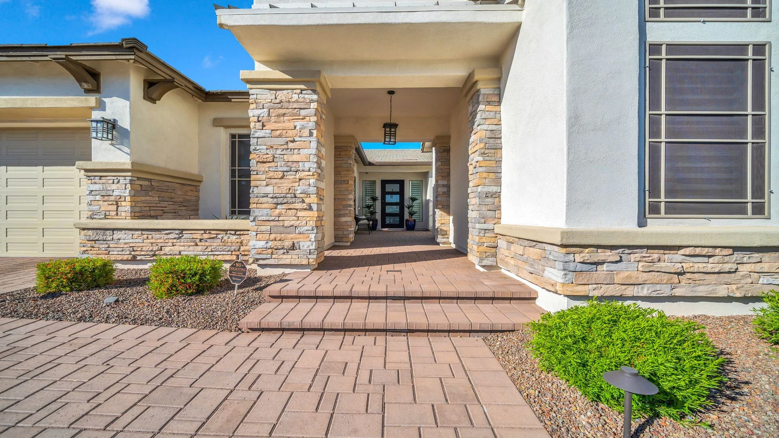 Front entrance of a house with stone pillars and a brick path