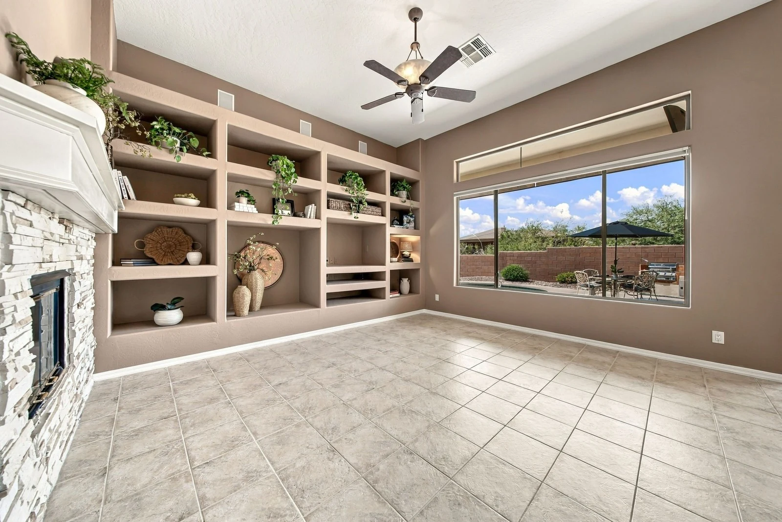 Empty family room with a stone fireplace and built-in shelves