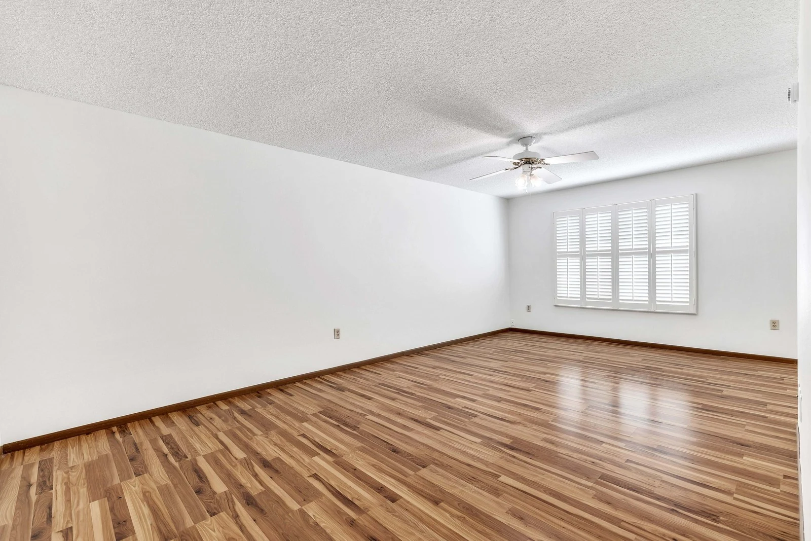 Vacant living room with wood floors and plantation shutters