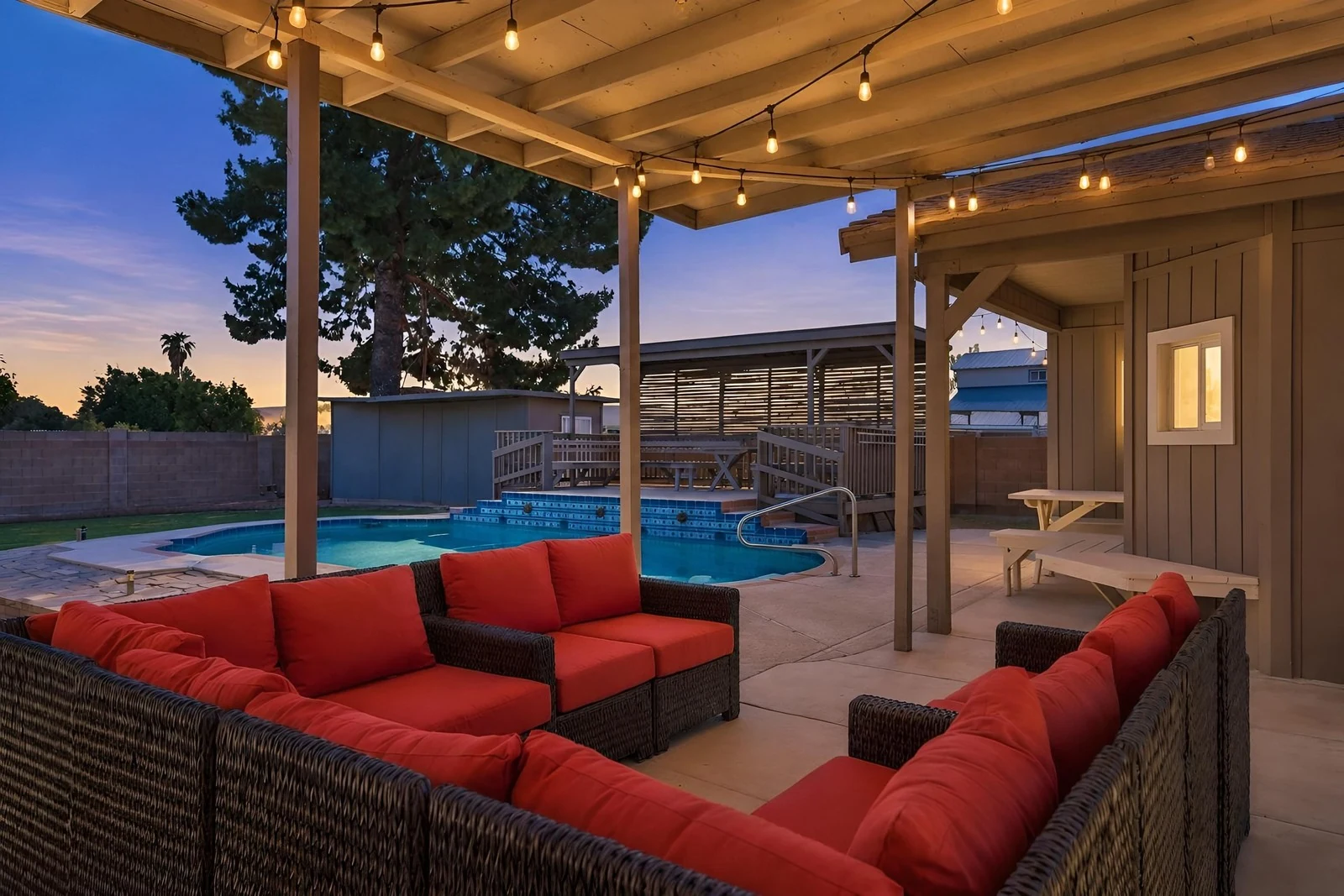 Virtual twilight of a covered patio with string lights and a pool