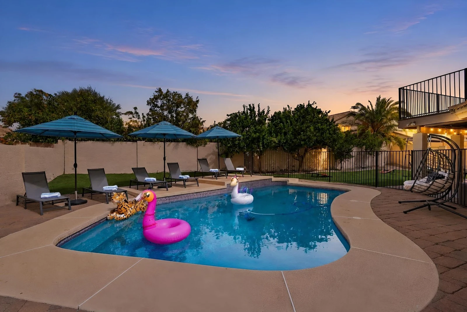 Virtual twilight of a backyard pool with umbrellas and floats