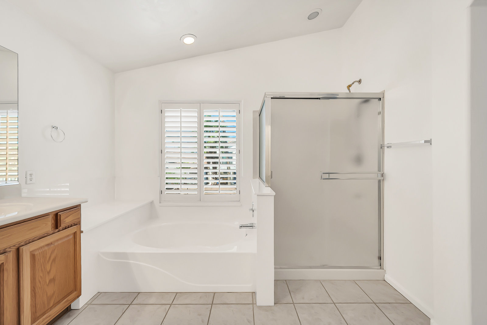 Spacious bathroom with white tub, glass shower, and wooden vanity.