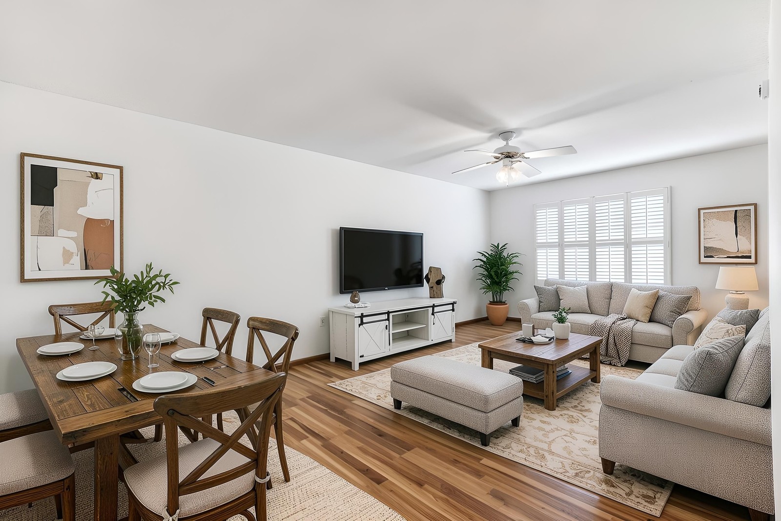 The same room virtually staged with a sectional, dining table and TV wall