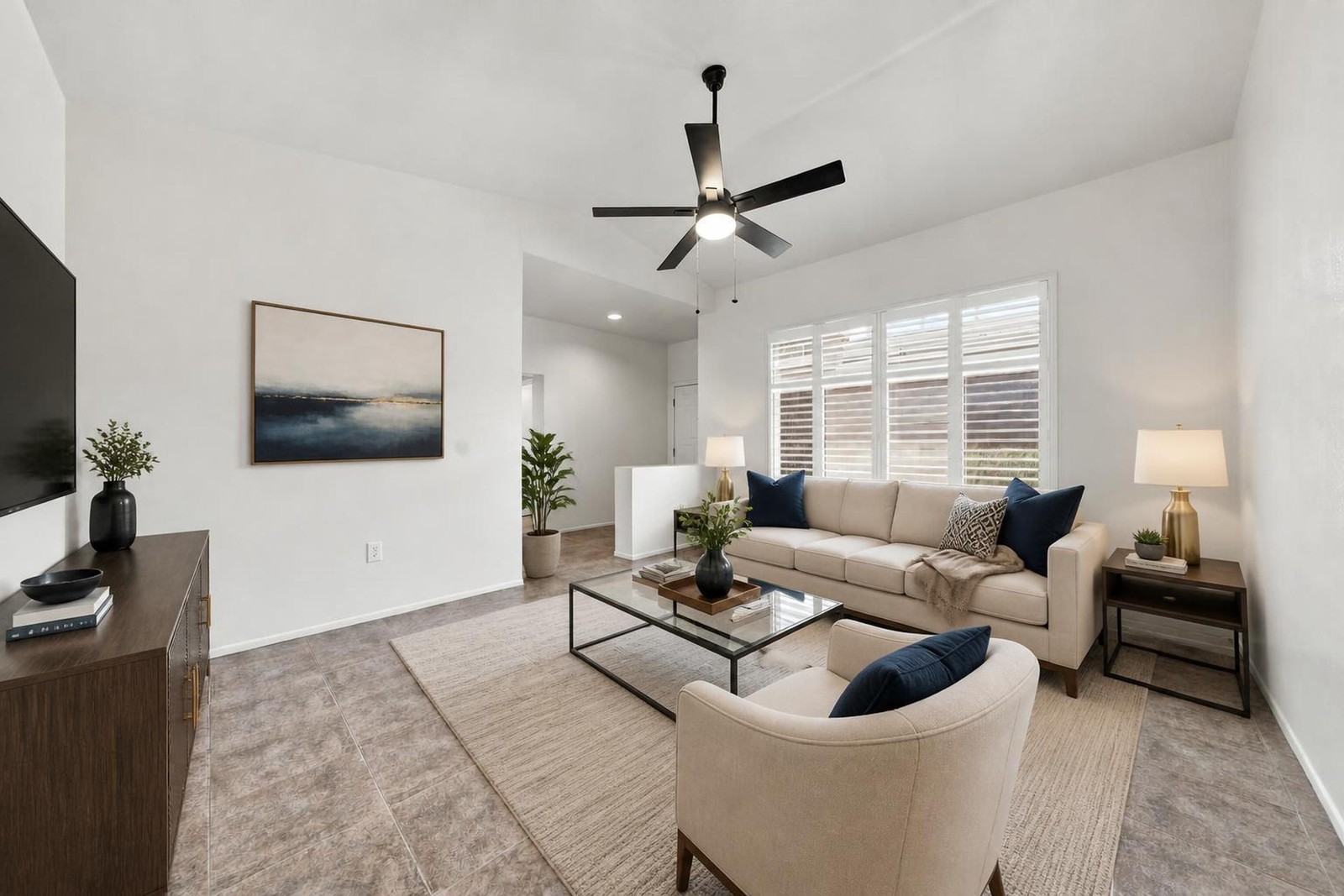The same living room virtually staged with a sofa, accent chair, art and lamps
