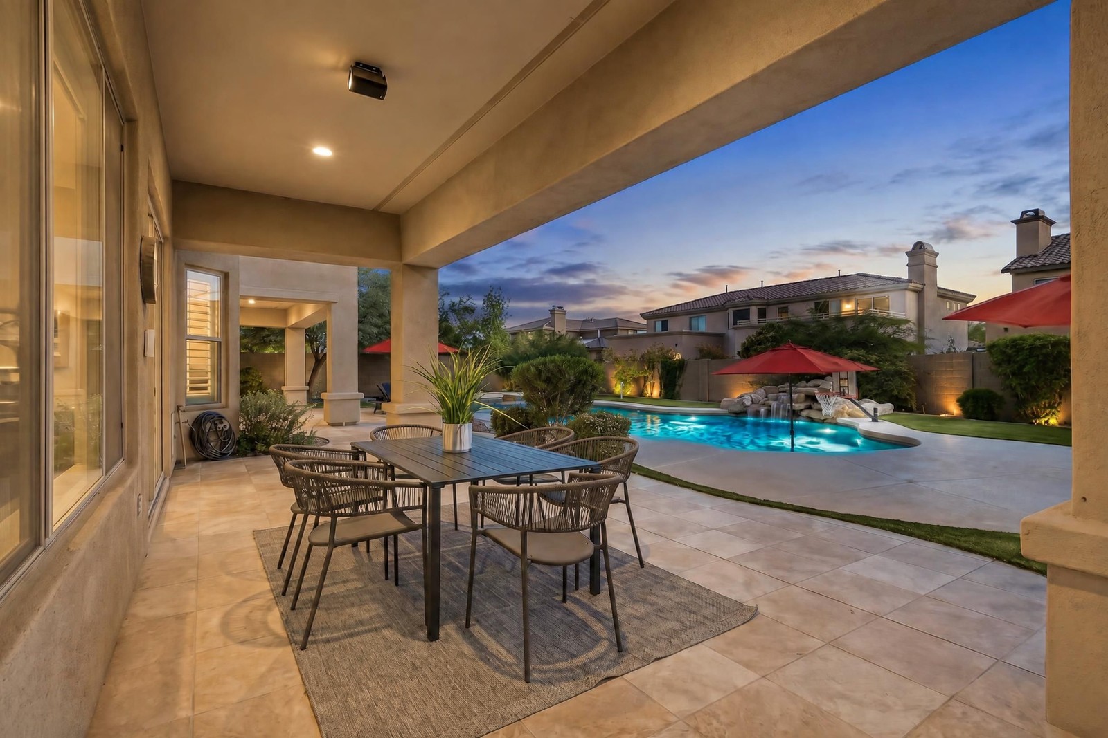 The same covered patio and pool as a virtual twilight with pool and landscape lights on