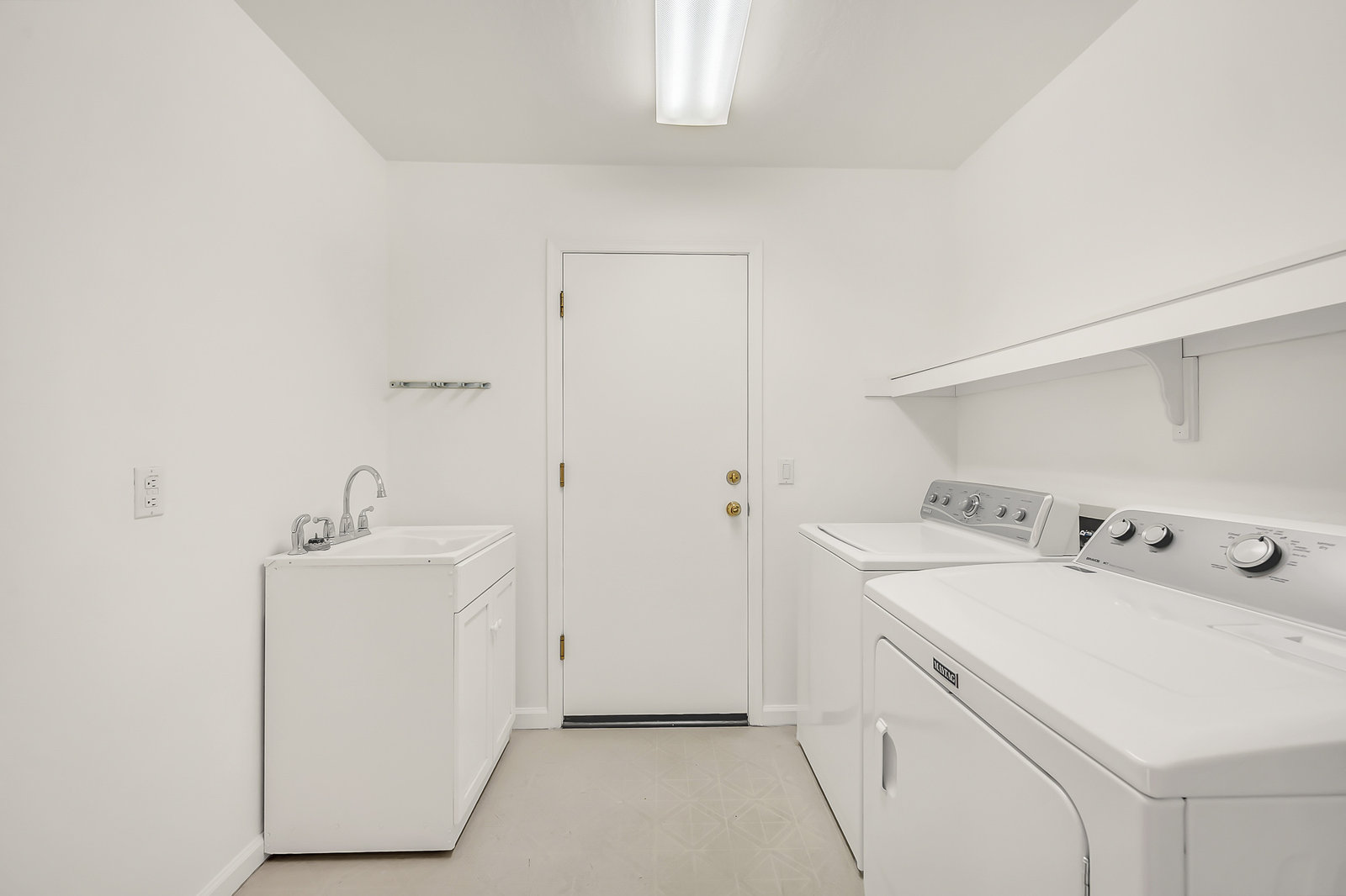 White laundry room with sink, washer, and dryer